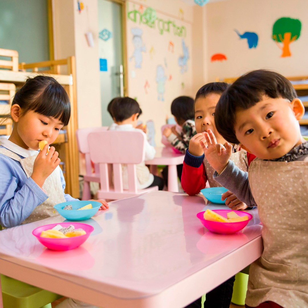 Imagem de crianças em uma mesa, merendando.